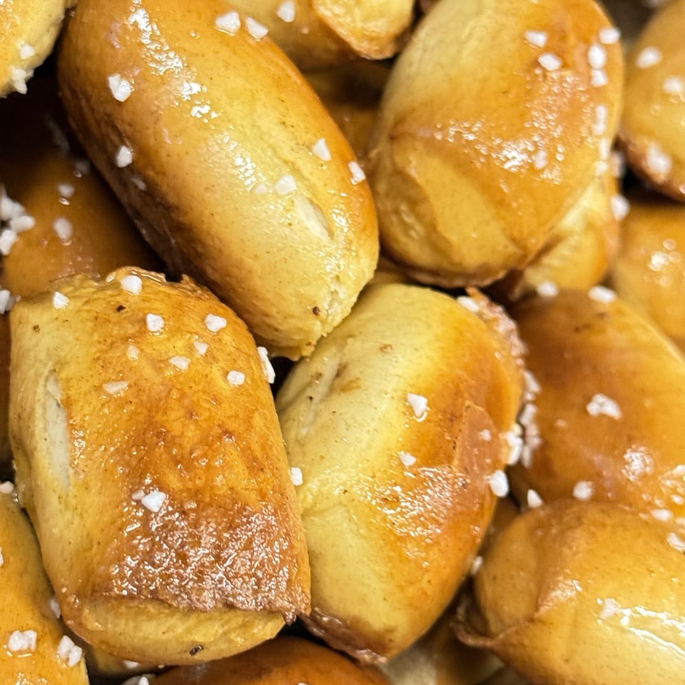 Close-up of golden-brown pretzel bites, glistening with butter and sprinkled with coarse salt.