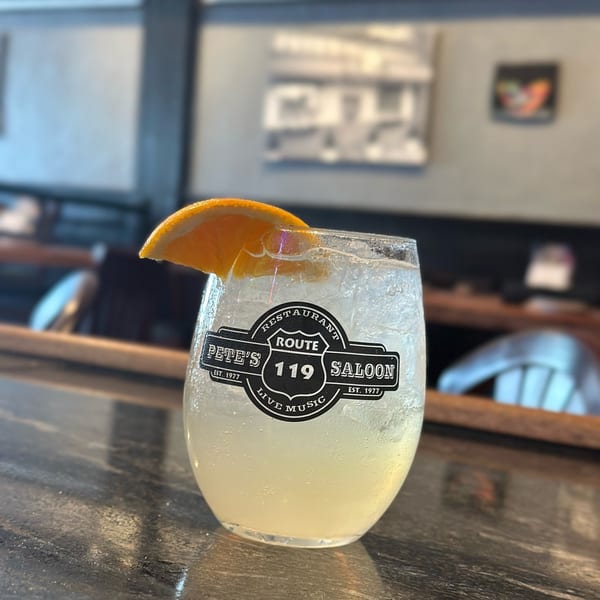 Pete's Saloon & Restaurant branded cocktail with an orange slice on a bar top.