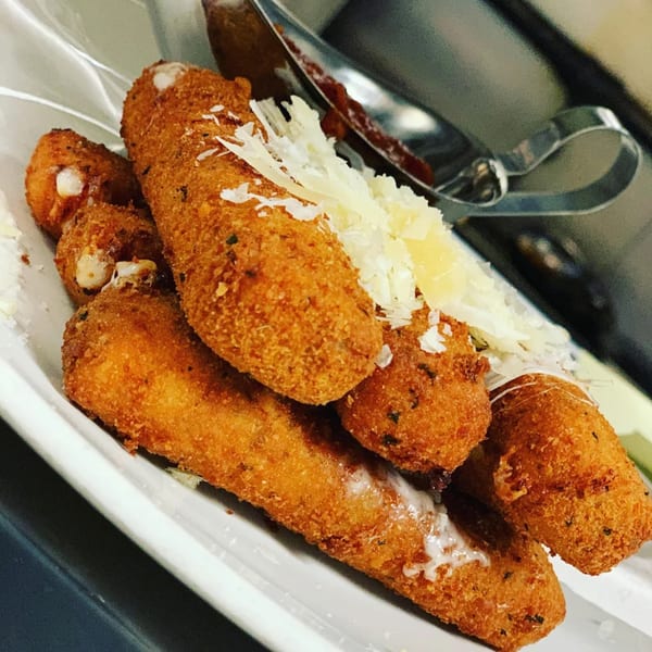 Crispy mozzarella sticks with melted cheese and grated Parmesan, served with marinara sauce at Pete's Saloon.