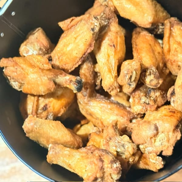 A black plate piled with golden-brown fried pastry rolls, some showing dark filling at their ends.